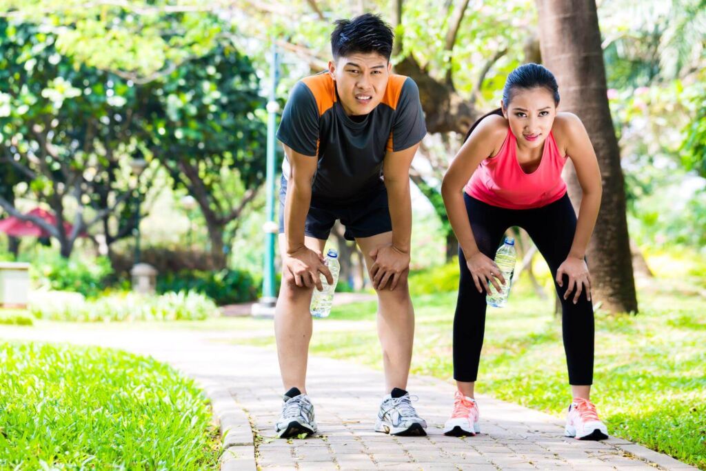 Chinese man and woman are out of breath after jogging in city park